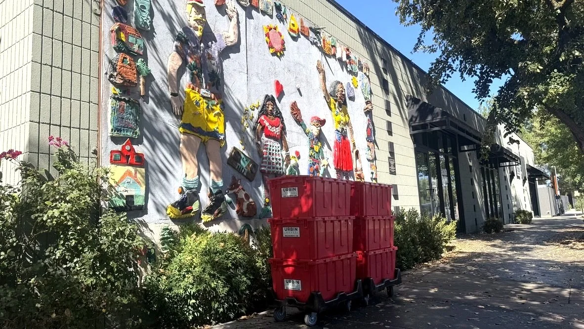 Red moving boxes outside near a mural in Davis California
