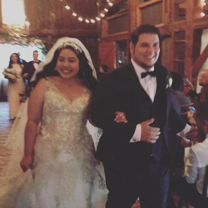 Bride and groom smiling and walking arm in arm at their wedding reception.
