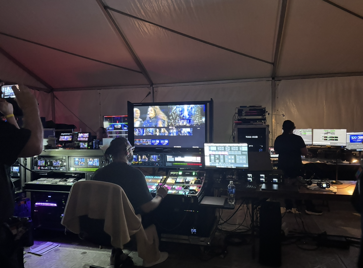 Inside a television broadcasting or production truck with multiple monitors, control panels, and operators working on the technical setup for a live event or broadcast.