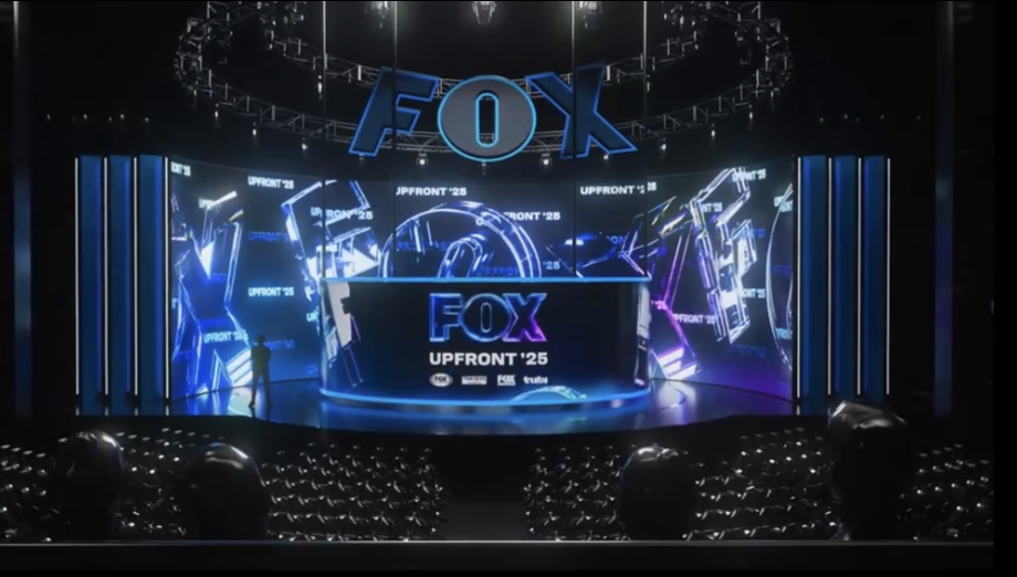 Stage with large screens displaying the FOX logo and the text 'UPFRONT '25', set for a presentation or event.