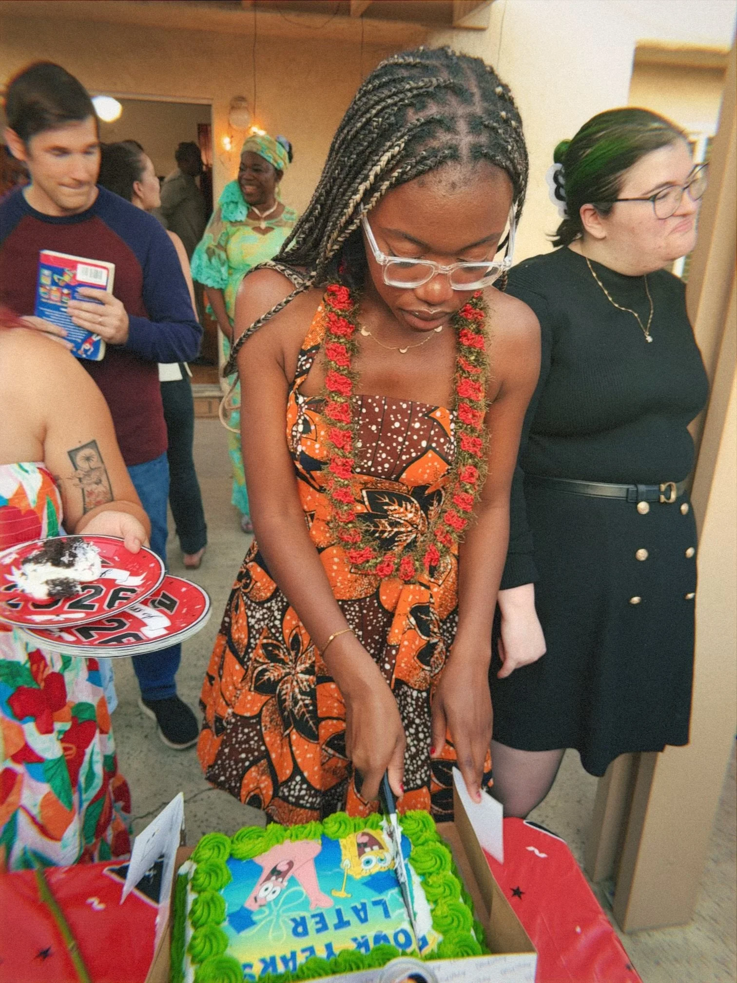 People at a birthday party gathering around a cake with a SpongeBob SquarePants theme.