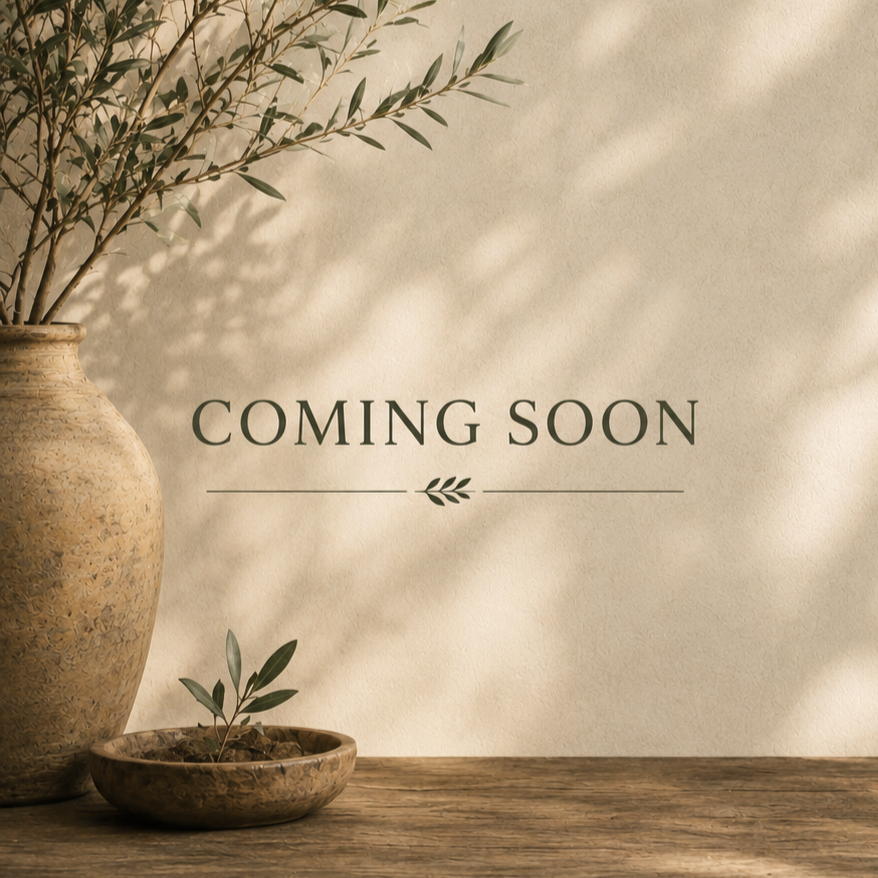A beige textured background with shadowed leaves, featuring a large ceramic vase with olive branches and a small ceramic bowl with a tiny olive plant, over a wooden surface, with the text 'Coming Soon' in the center.