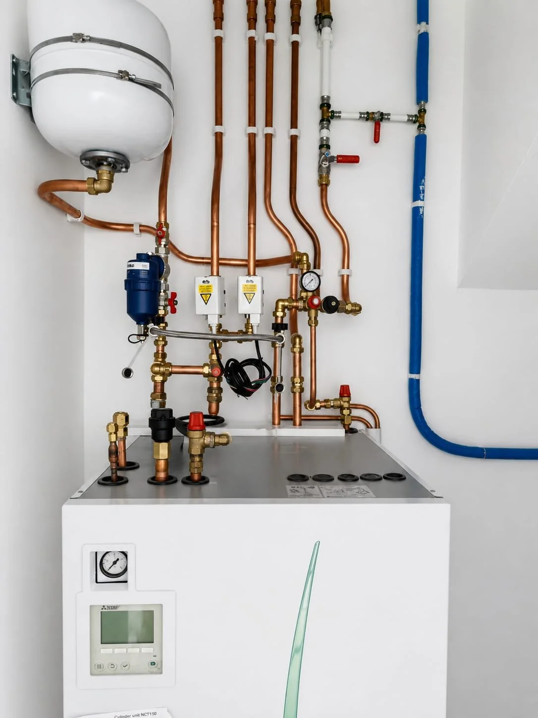 Indoor heatproof unit with copper pipes, pressure gauge, and control panel.