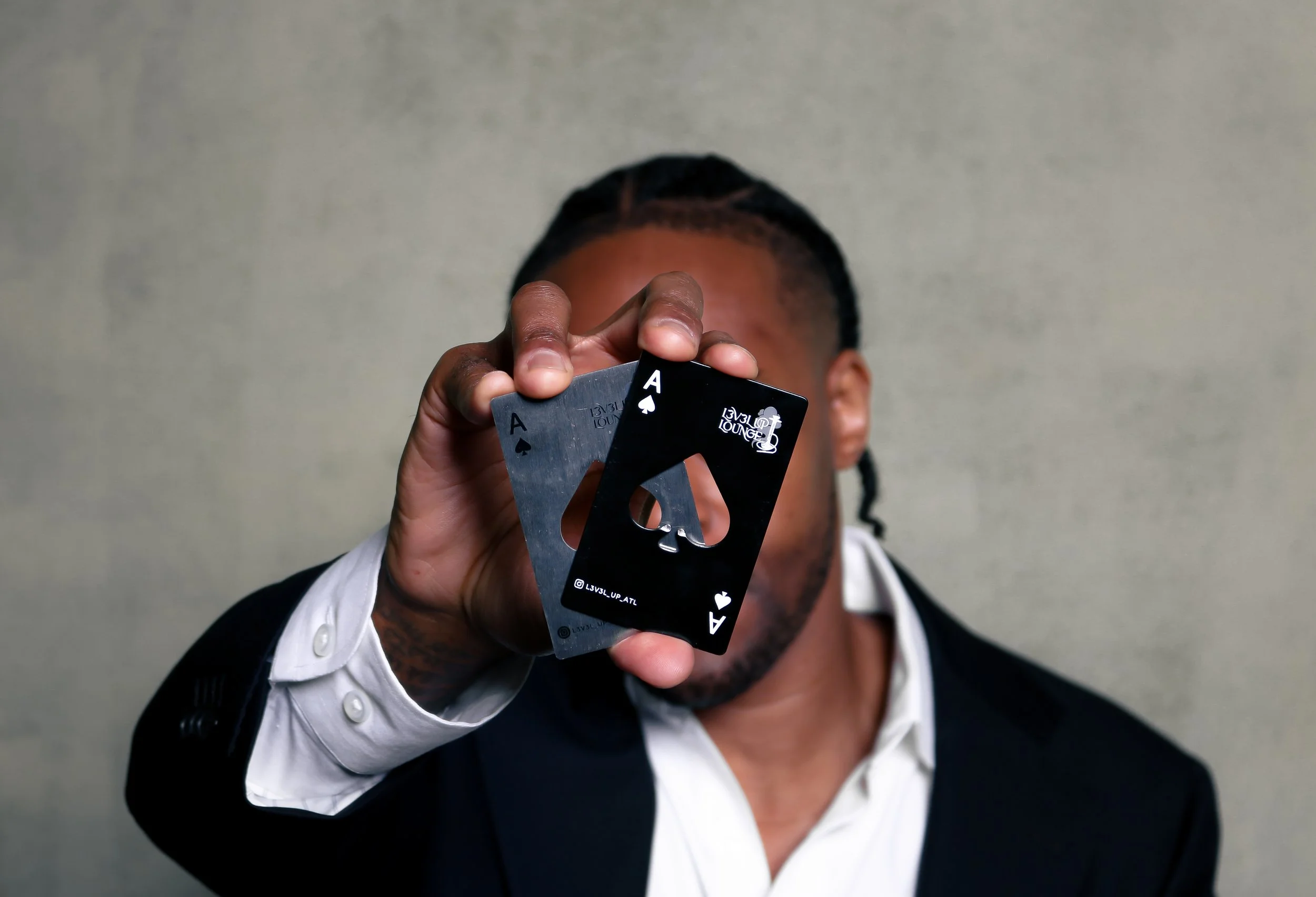 Person holding two playing cards, the Ace of Spades and the Ace of Clubs, in front of their face.