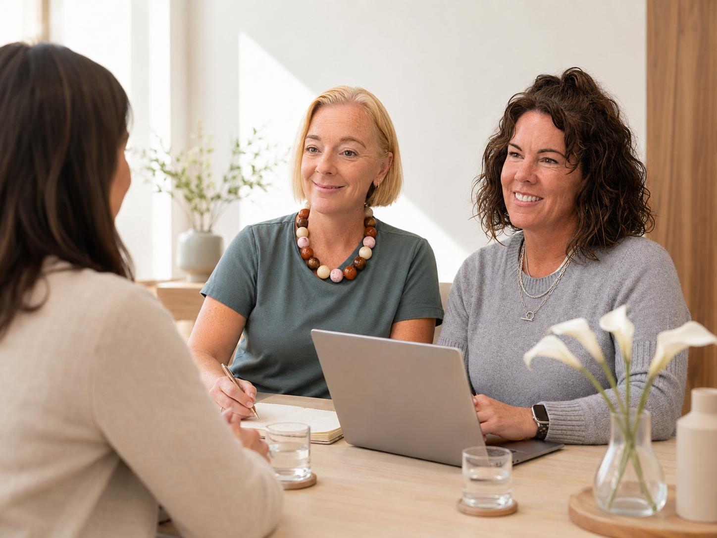 2 lexington wellness nurse practitioners sitting at a desk discussing weight loss treatments with a woman in a comfortable clinic setting.