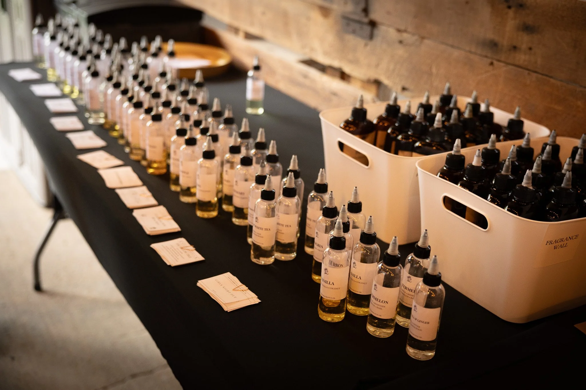 Display of small bottles of fragrance oils on a table with labels and a tray in the background.