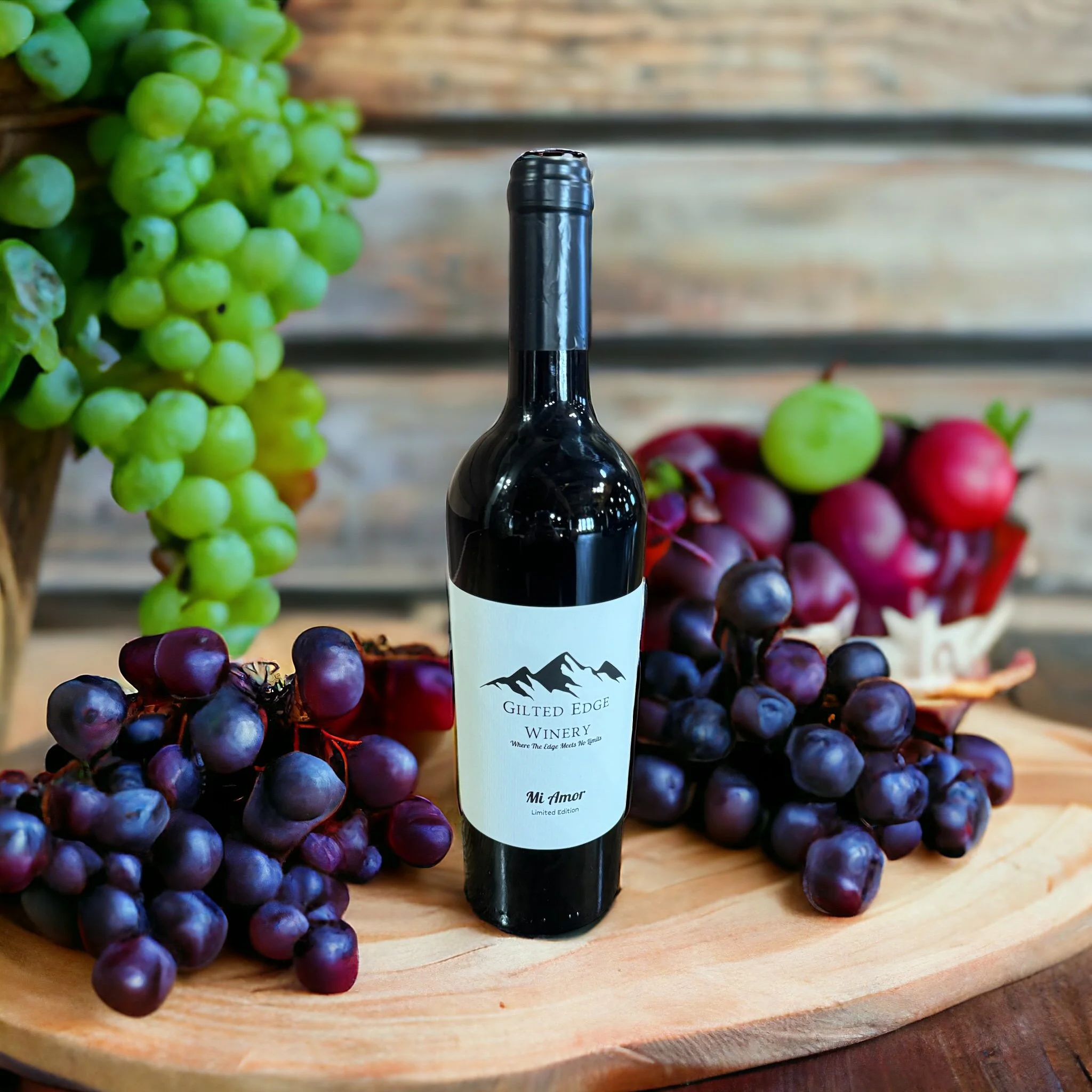 A wine bottle labeled 'Gilded Edge Winery' surrounded by green and purple grapes on a wooden surface.