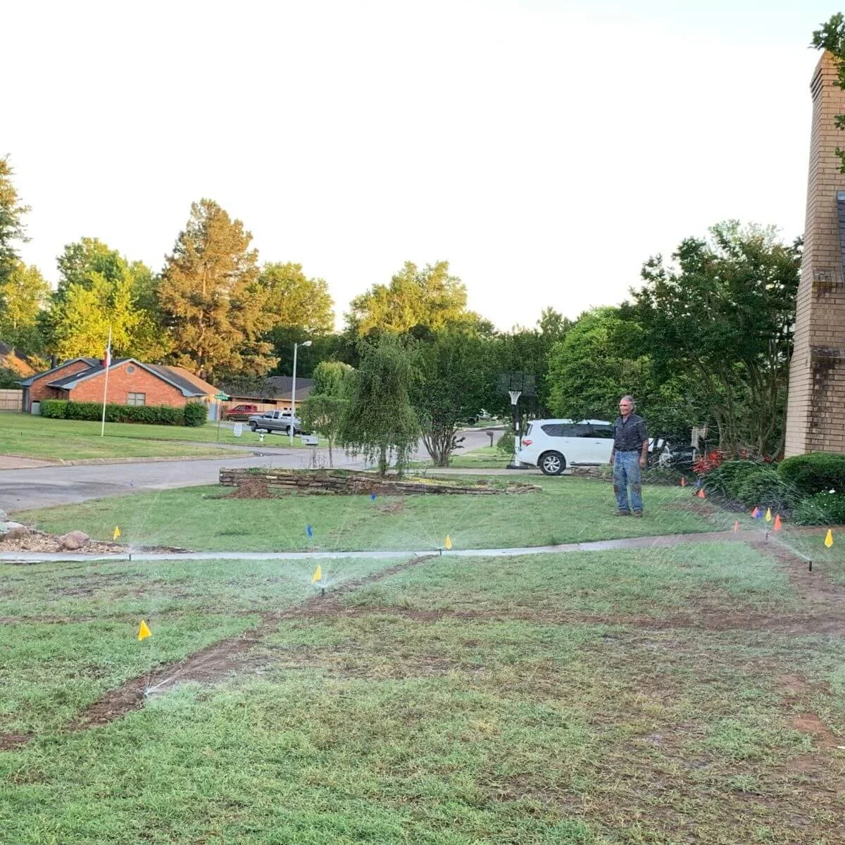 Sprinkler system shown on partially landscaped yard, marked with small flags in northeast Texas.