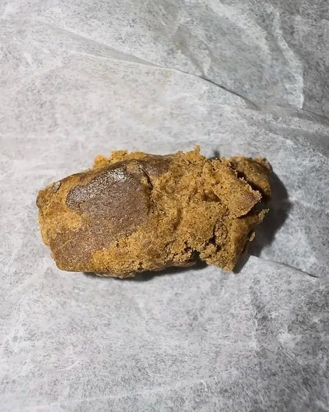 Ein frittiertes Lebensmittel, vermutlich Hühnchen, auf grauem Papier.
