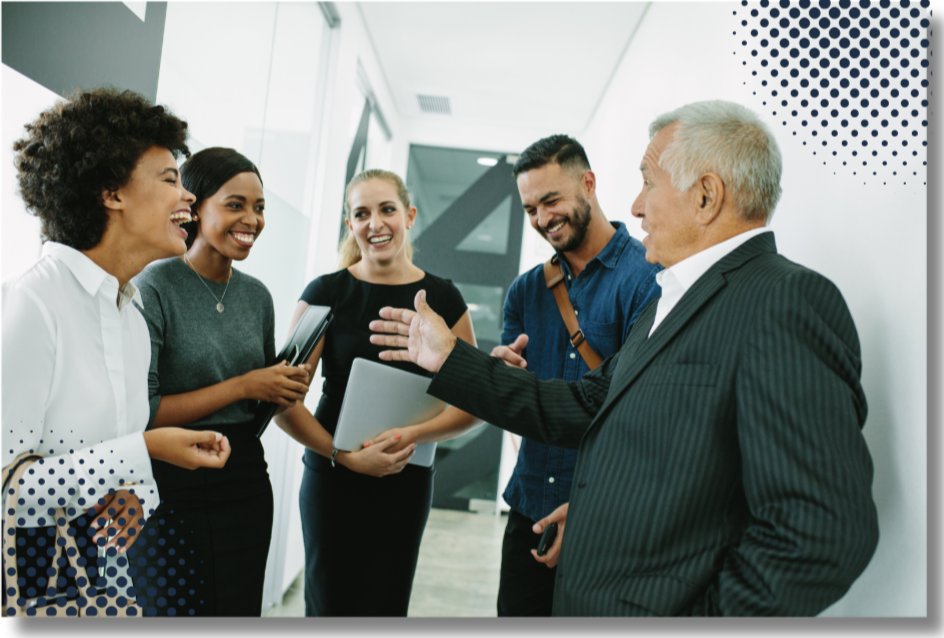 Five diverse professionals in business attire engaging in a lively conversation in a modern office hallway.