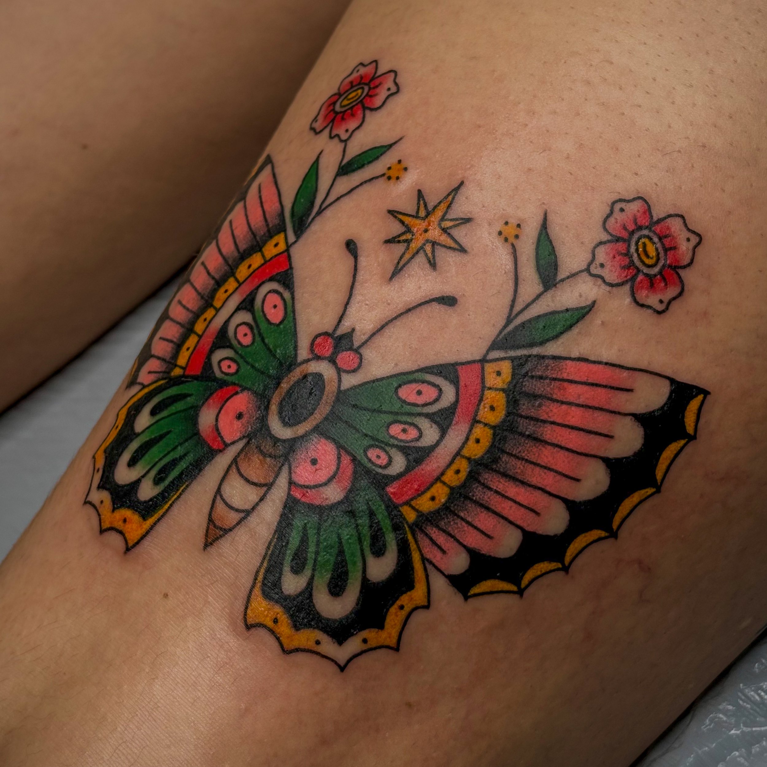 Colorful tattoo of flowers and a star on a person's skin.