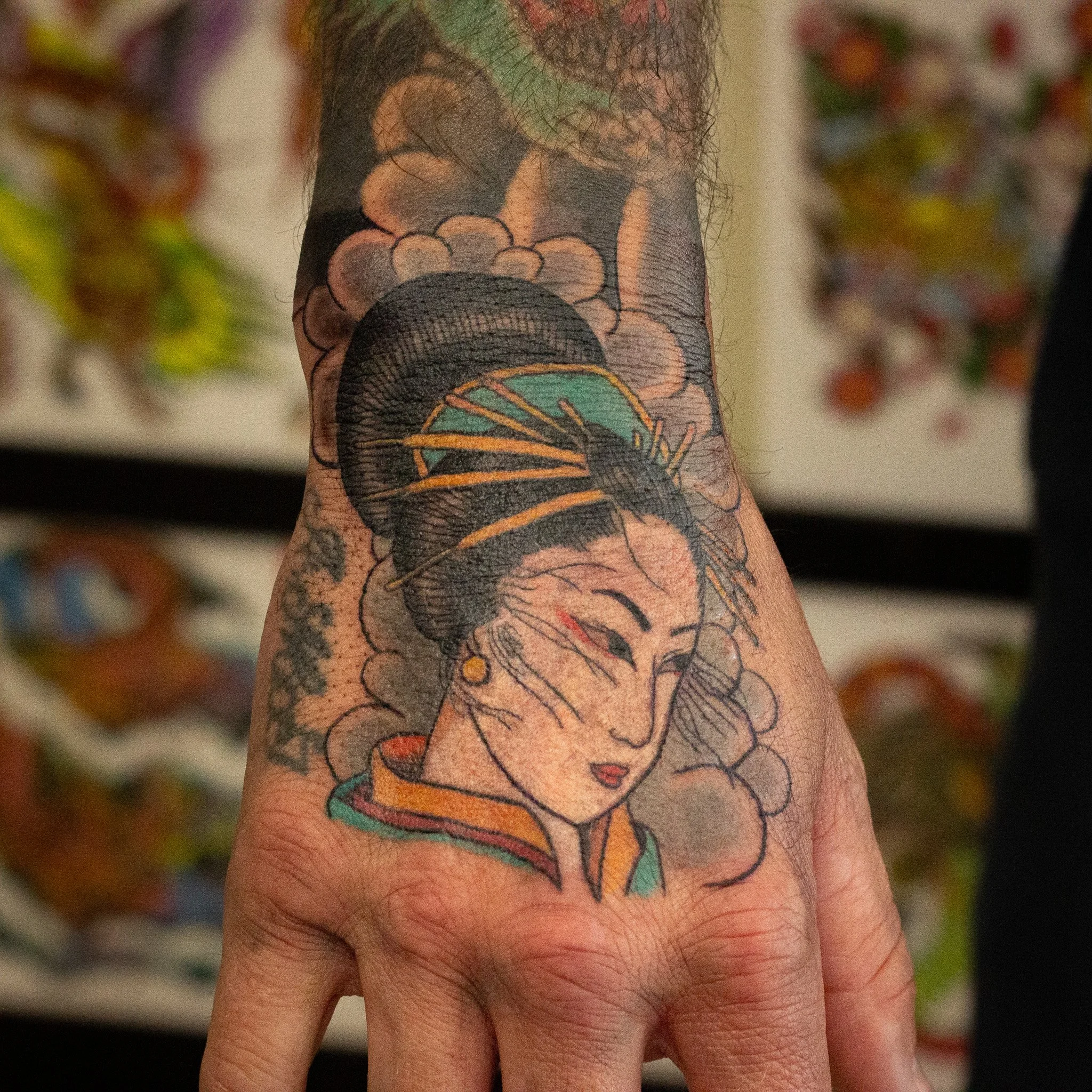 A japanese tattoo of a woman's face with colorful elements on the hand.