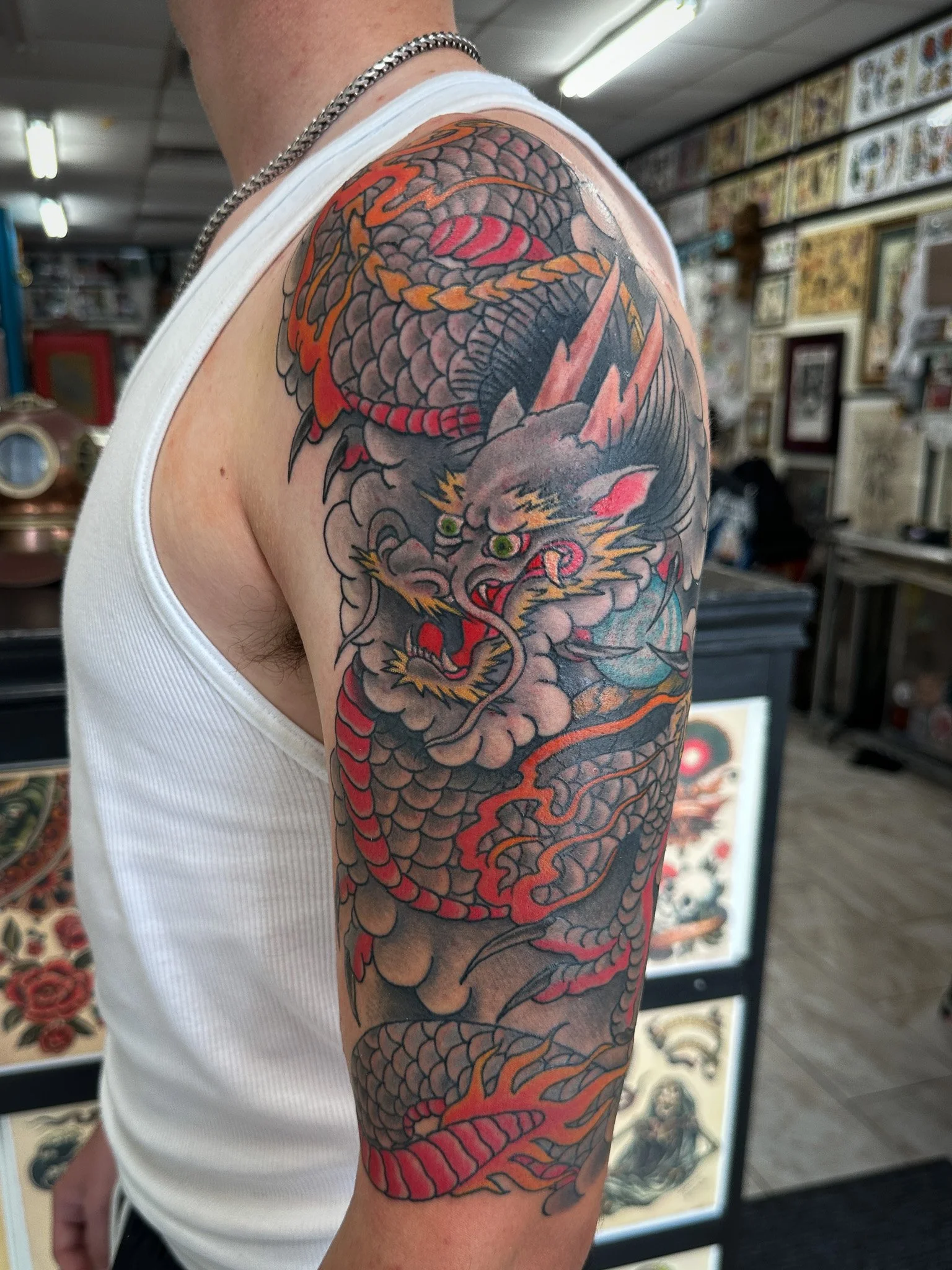 Colorful Japanese-style dragon tattoo on a person's upper arm showing a fierce dragon with scales, claws, and a flowing body.