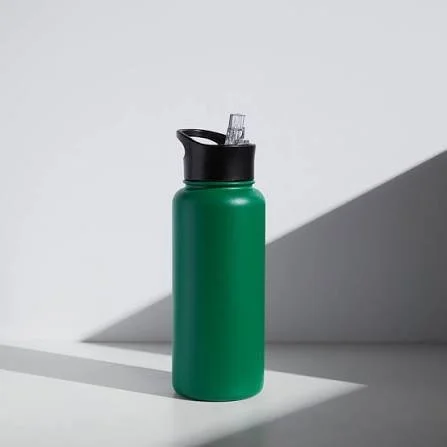 Green reusable water bottle with a black lid and a clear straw, placed on a white surface with shadows.