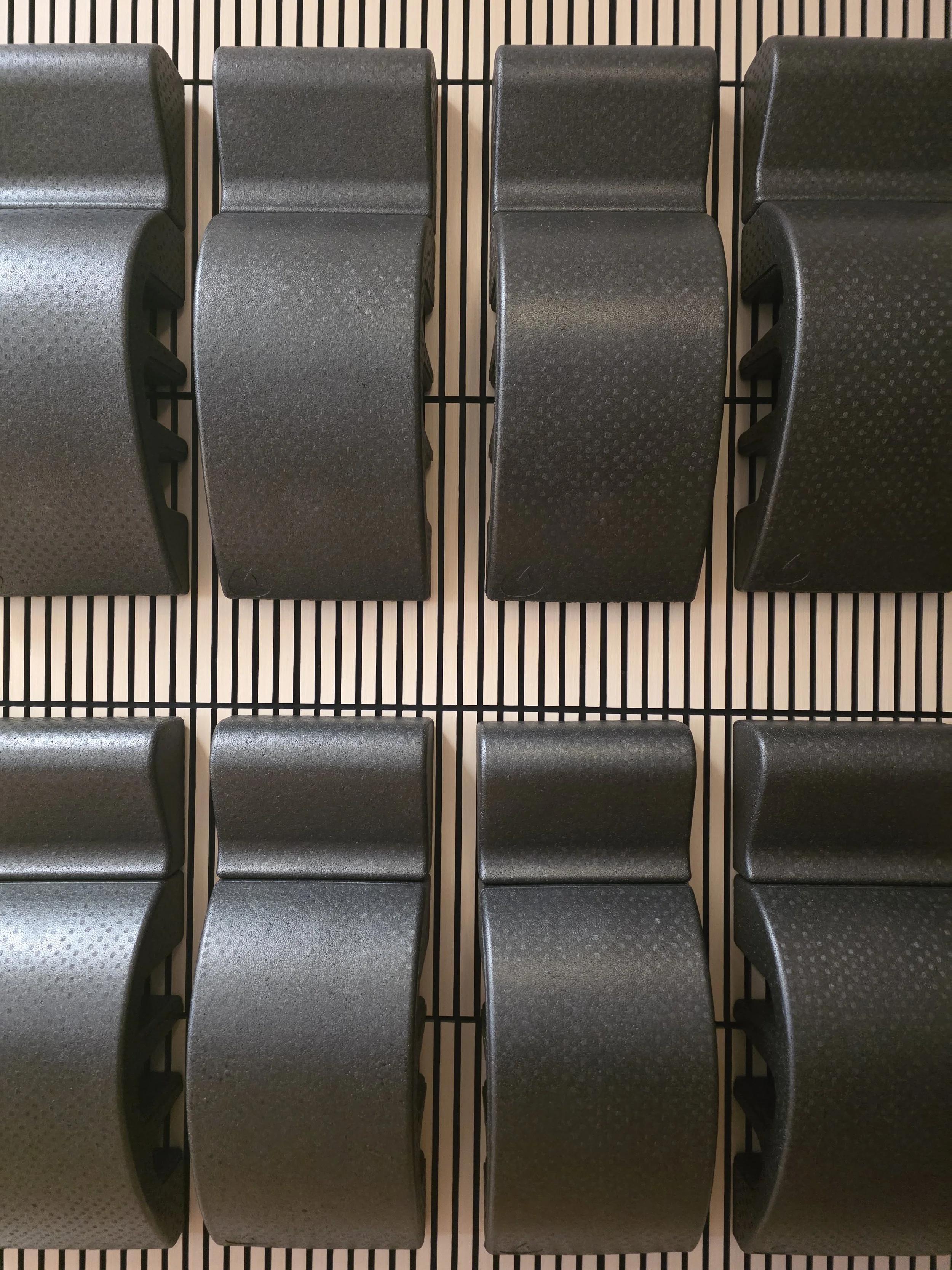 Rows of foam spinal correctors hung up against light-colored acoustical wood paneling.