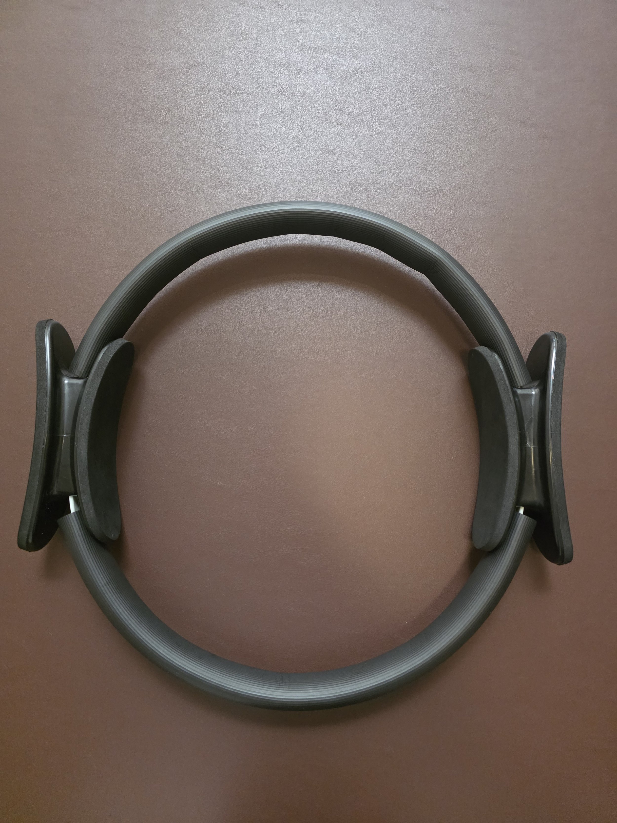 A black Magic Ring on a dark brown leather-light surface.
