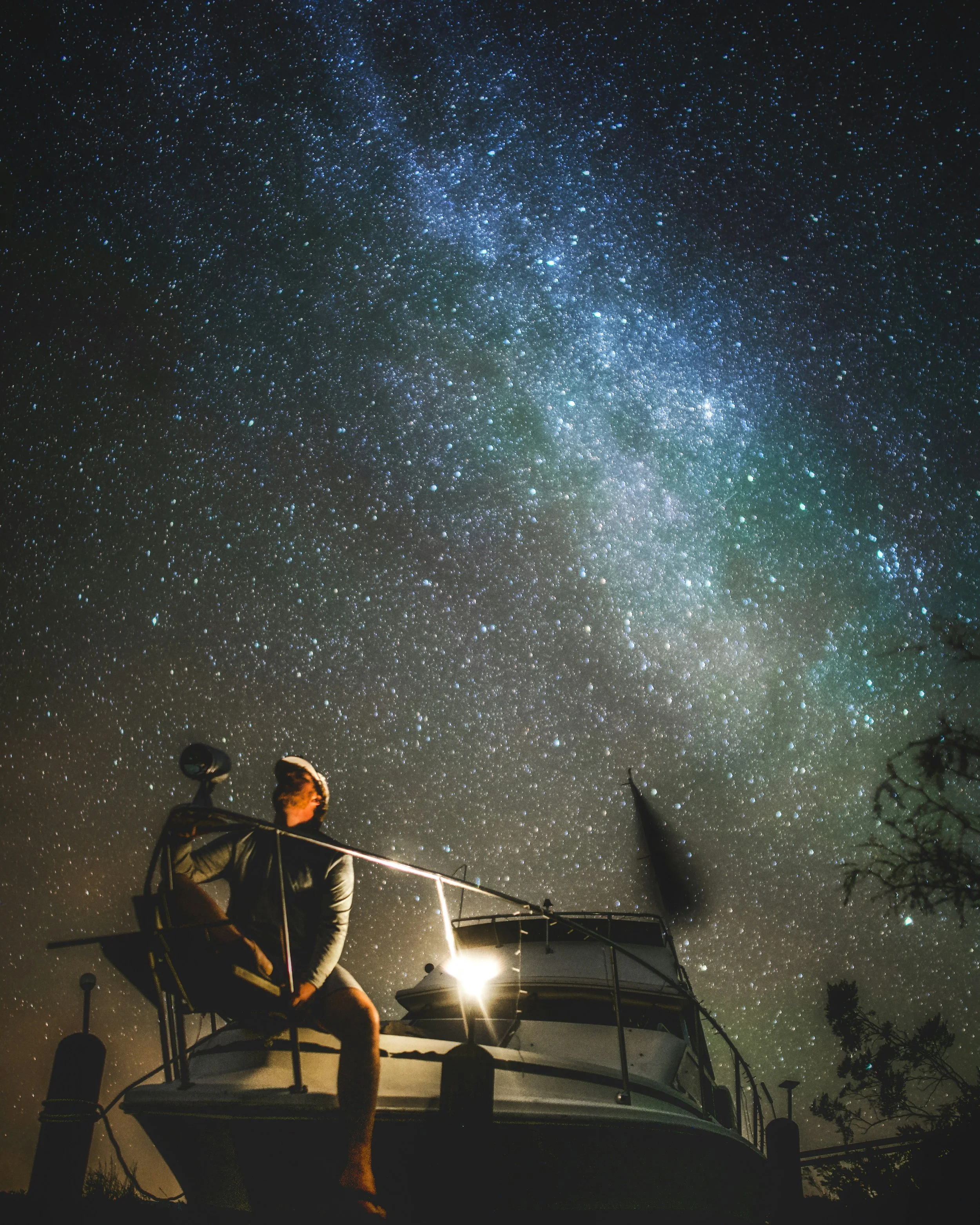 Person sitting on the deck of a boat in Florida during a starry night, with the Milky Way galaxy visible overhead.