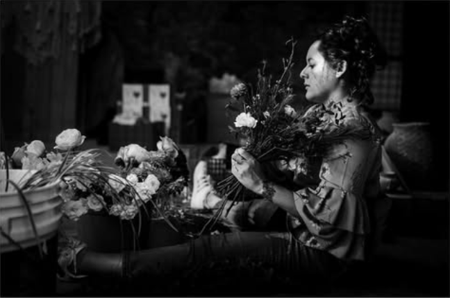 Black and white photograph of floral artist Eloisa Lazcano mindfully arranging local blooms following the slow flowers philosophy.