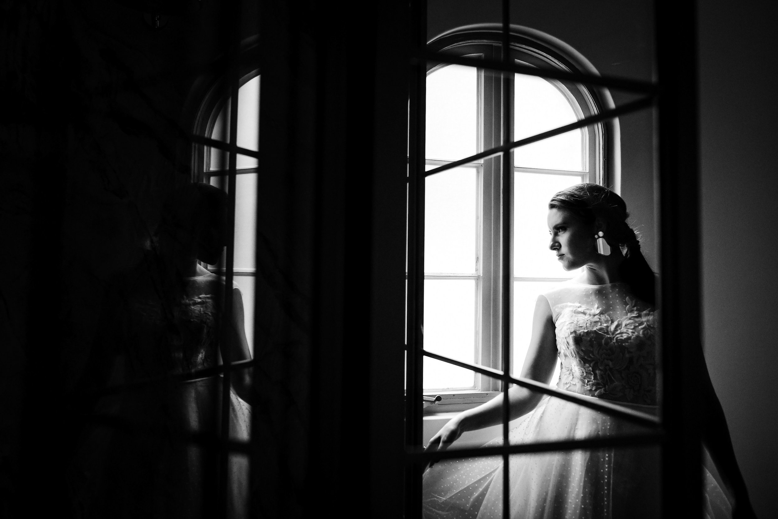 Fine art black and white wedding portrait of a bride by a window showcasing her bridal makeup and hair styling. By Juan Luis Jimenez at Luna Escondida.