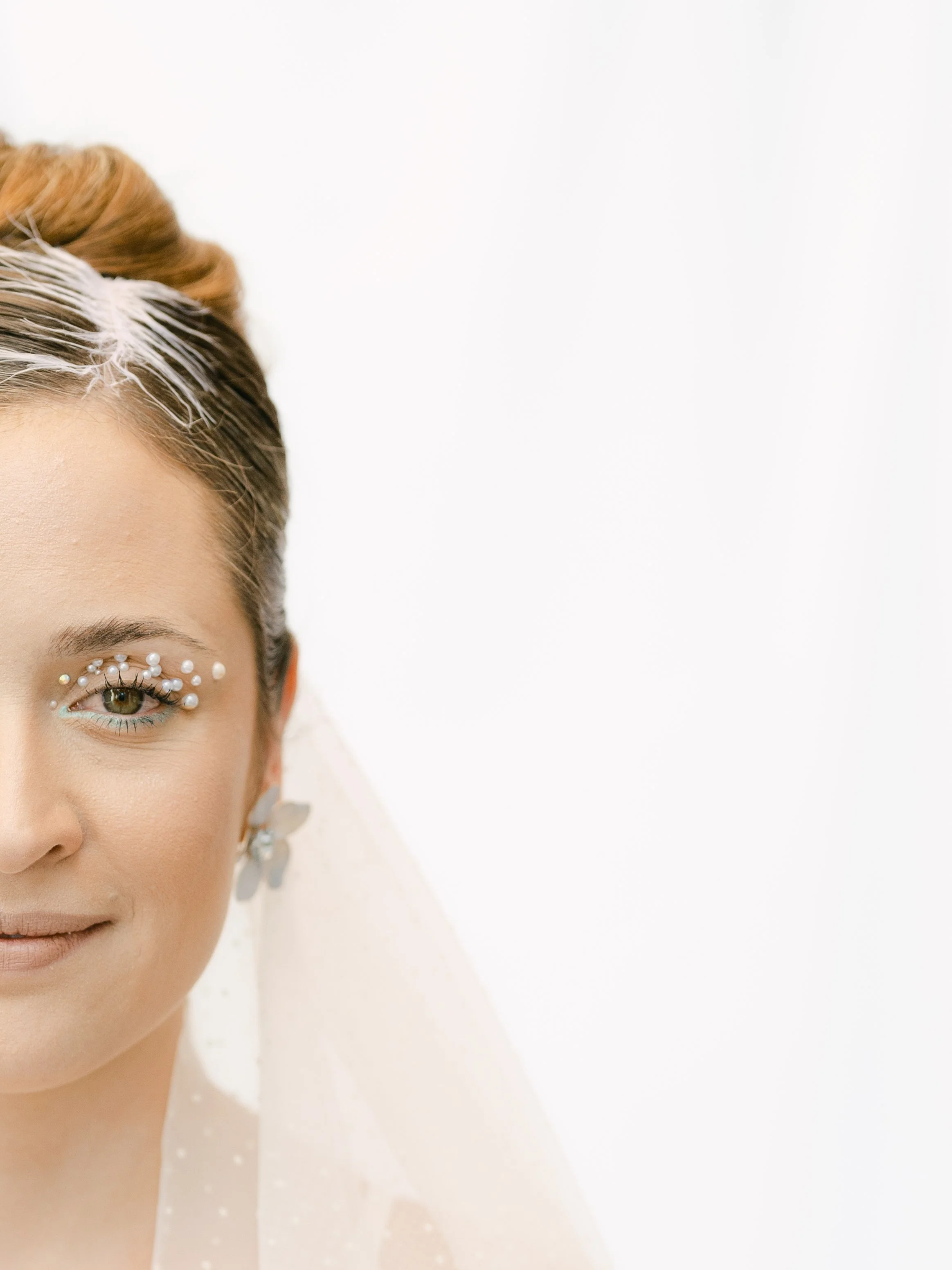 Editorial bridal beauty shot featuring a creative half-face portrait with delicate pearl eye embellishments by Erika Makeup Artist.