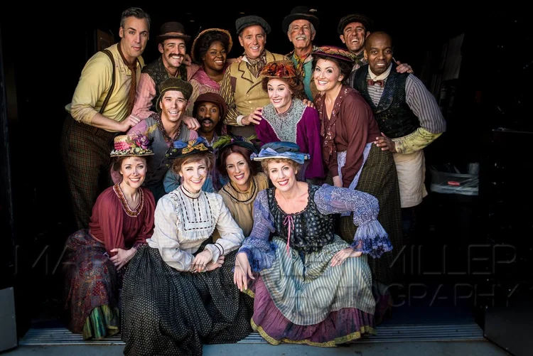 Group of people dressed in vintage clothing, smiling and posing together for a photo.