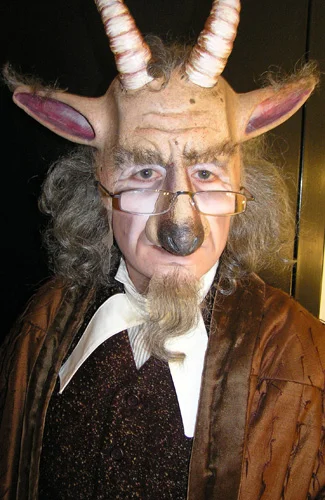 Person dressed in a costume with a goat mask, horns, and glasses.