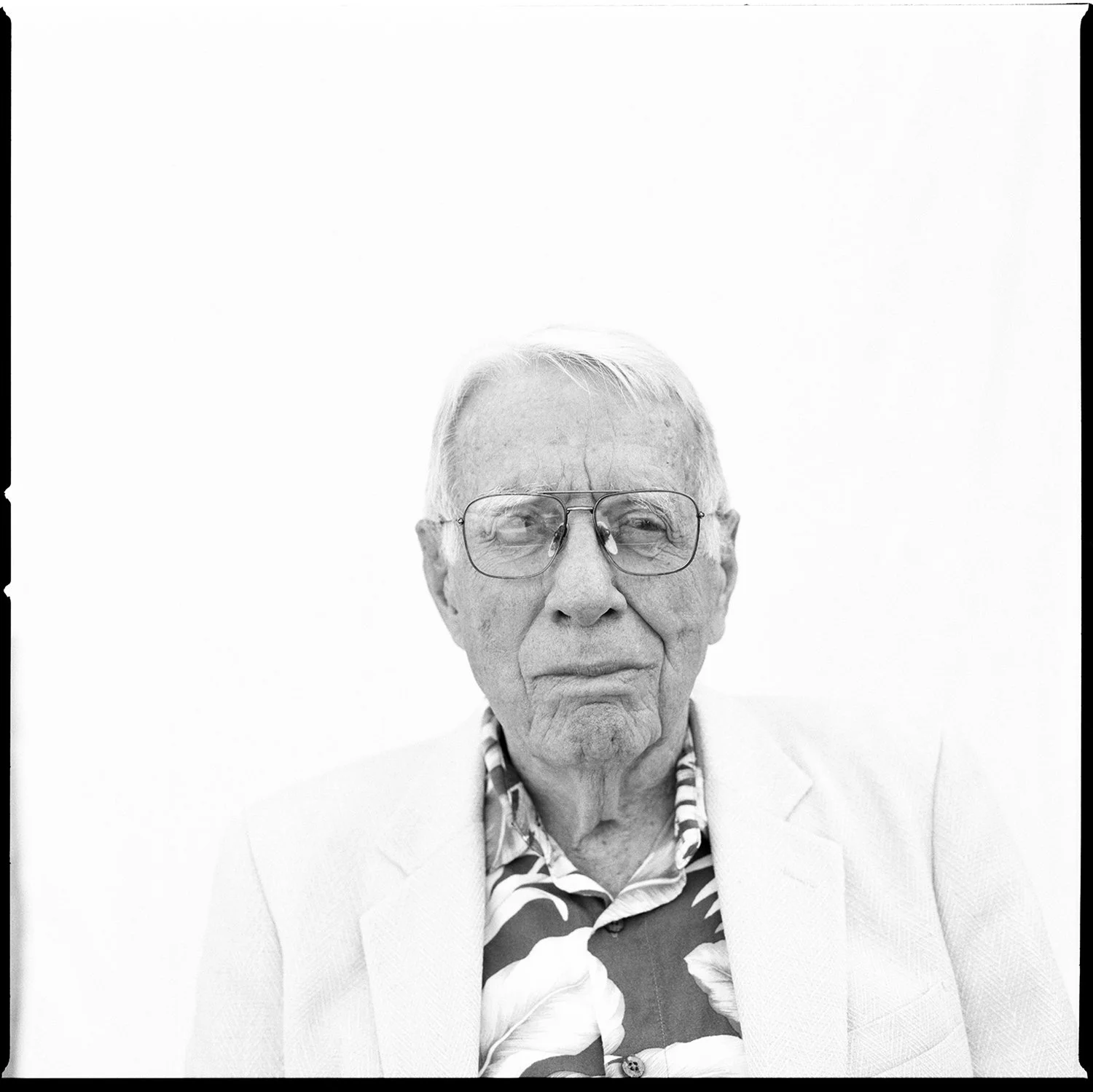 Elderly man in a floral shirt and glasses, black and white editorial portrait by Michael Rudin