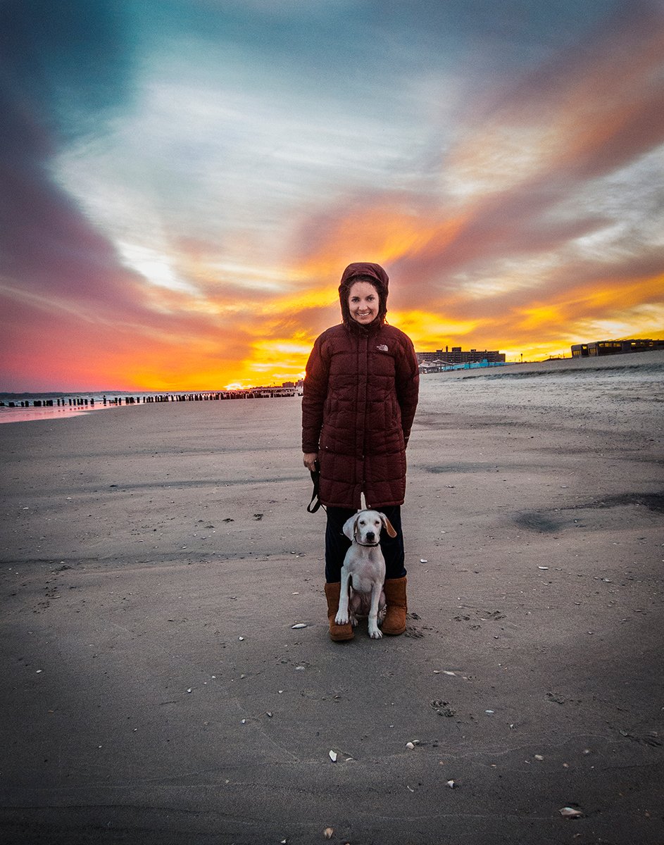 Woman and puppy standing on the beach at sunset, personal portrait by Michael Rudin