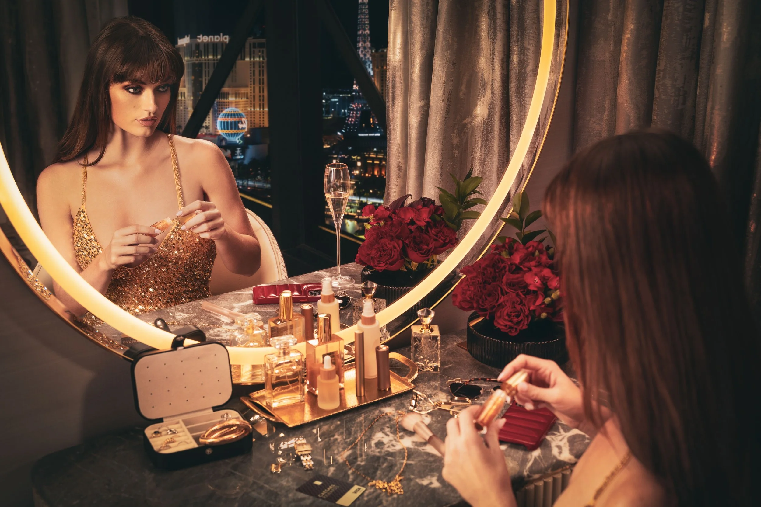 Woman applying makeup at hotel suite vanity mirror