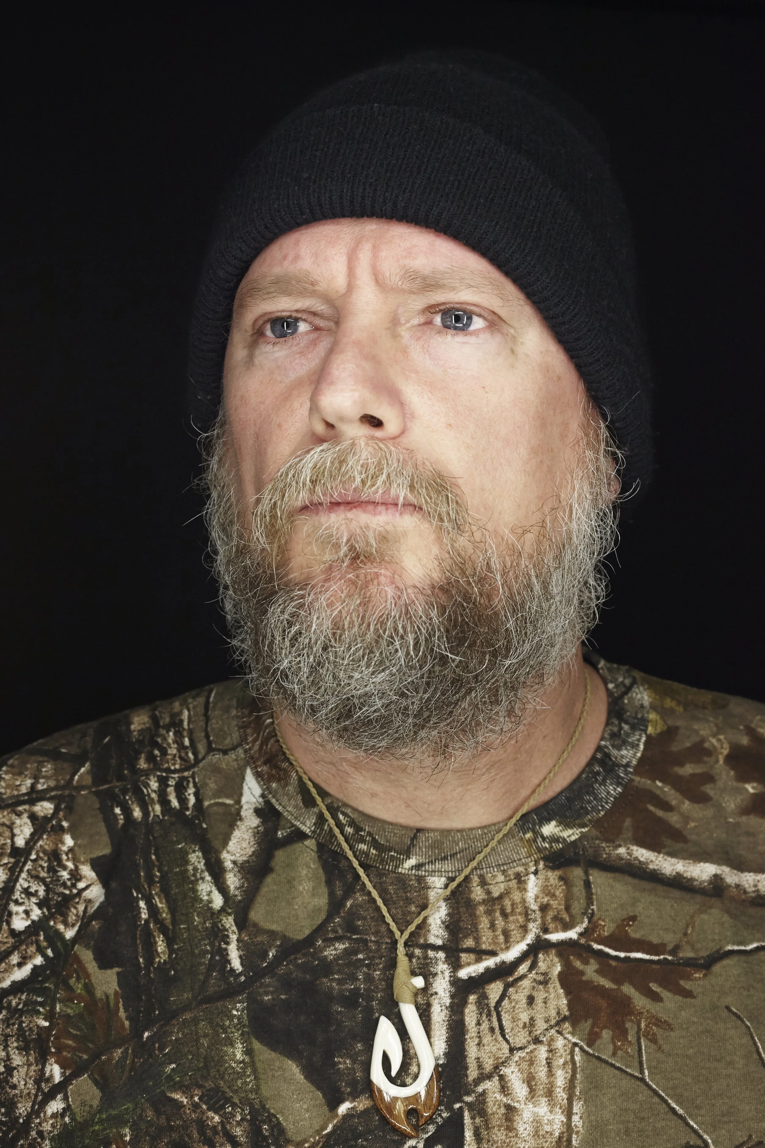 Man in a beanie and camo shirt, close-up editorial portrait by Michael Rudin
