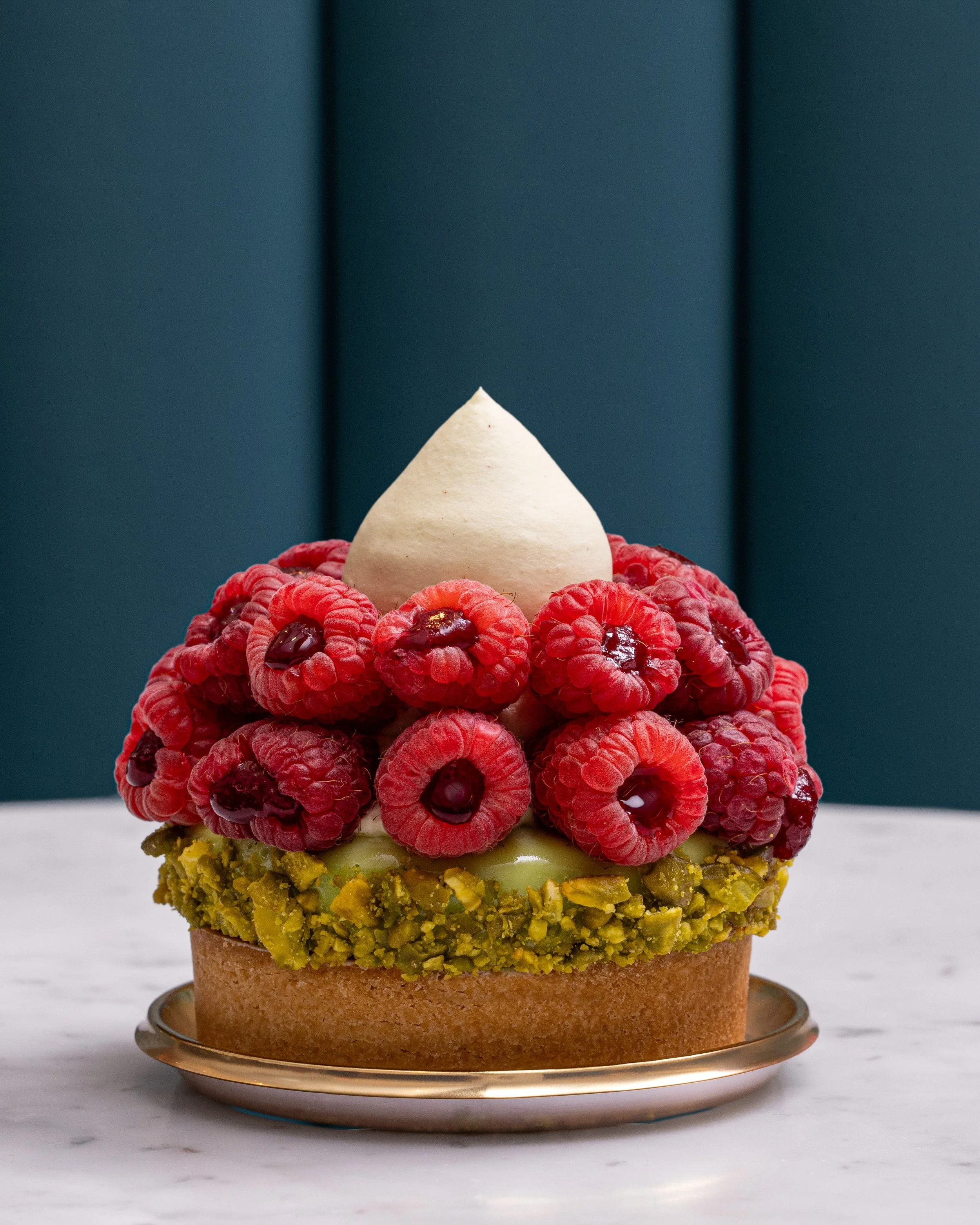 Pistachio tart topped with fresh raspberries and vanilla cream