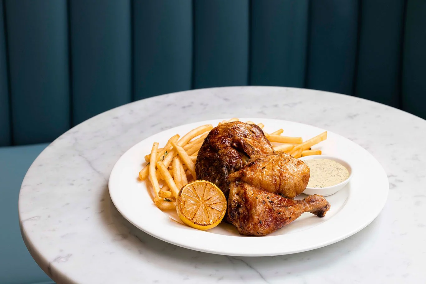 Plated rotisserie chicken and fries with charred lemon and herb aioli