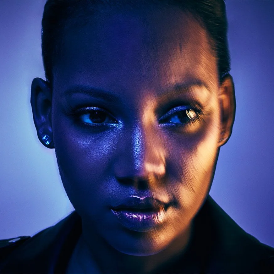 Close-up beauty-lit portrait of a woman with dramatic blue and orange lighting, photographed by Michael Rudin