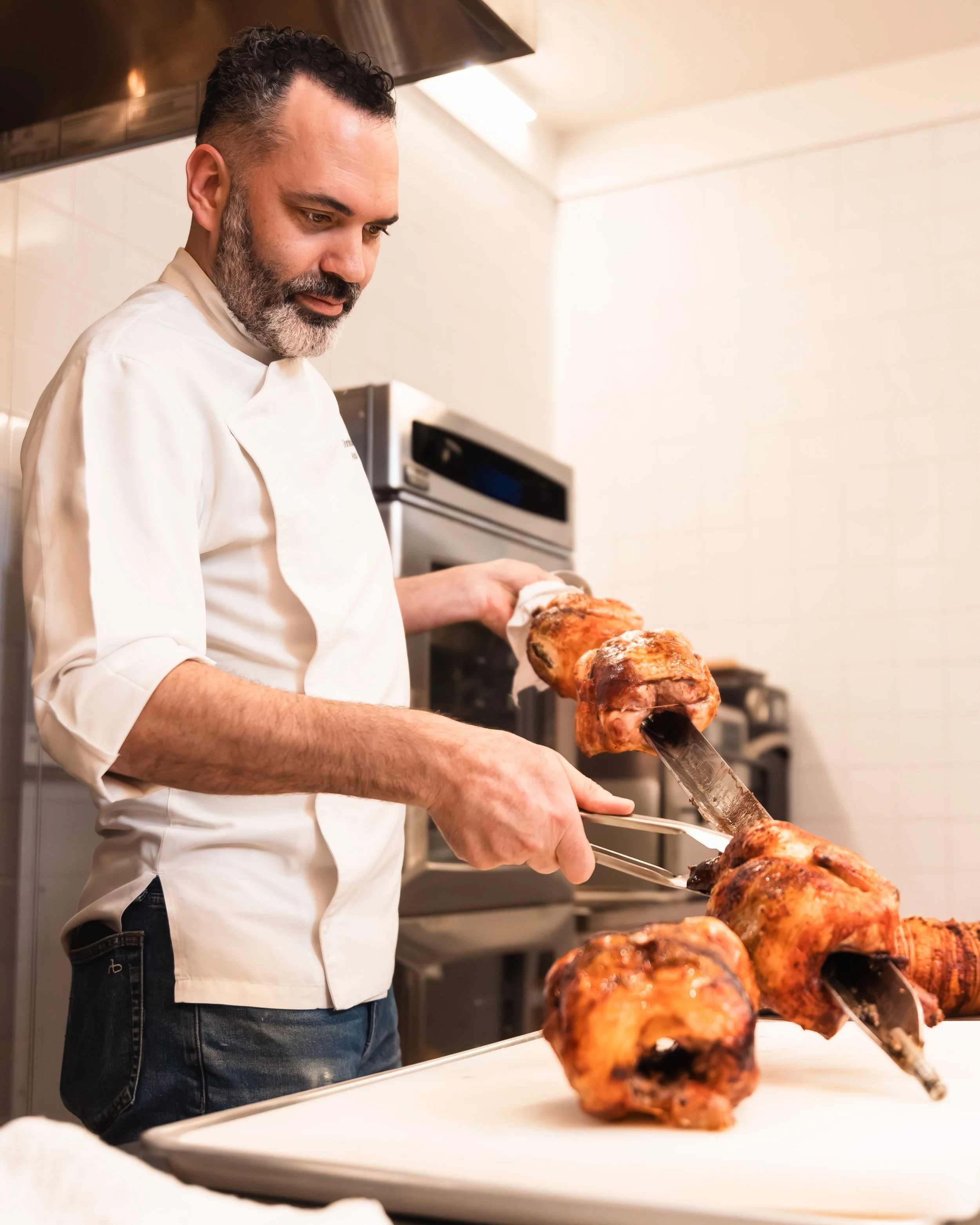 Dominique Ansel carving rotisserie chicken in the kitchen