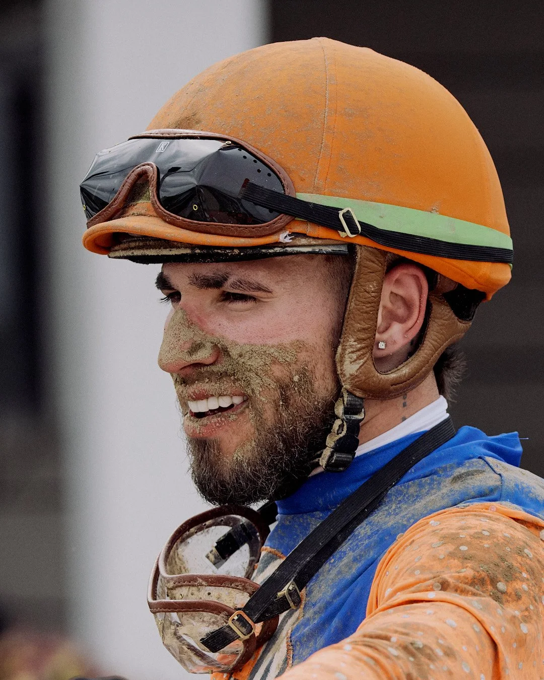 Mud-splattered jockey smilling after a race at Horseshoe Indianapolis
