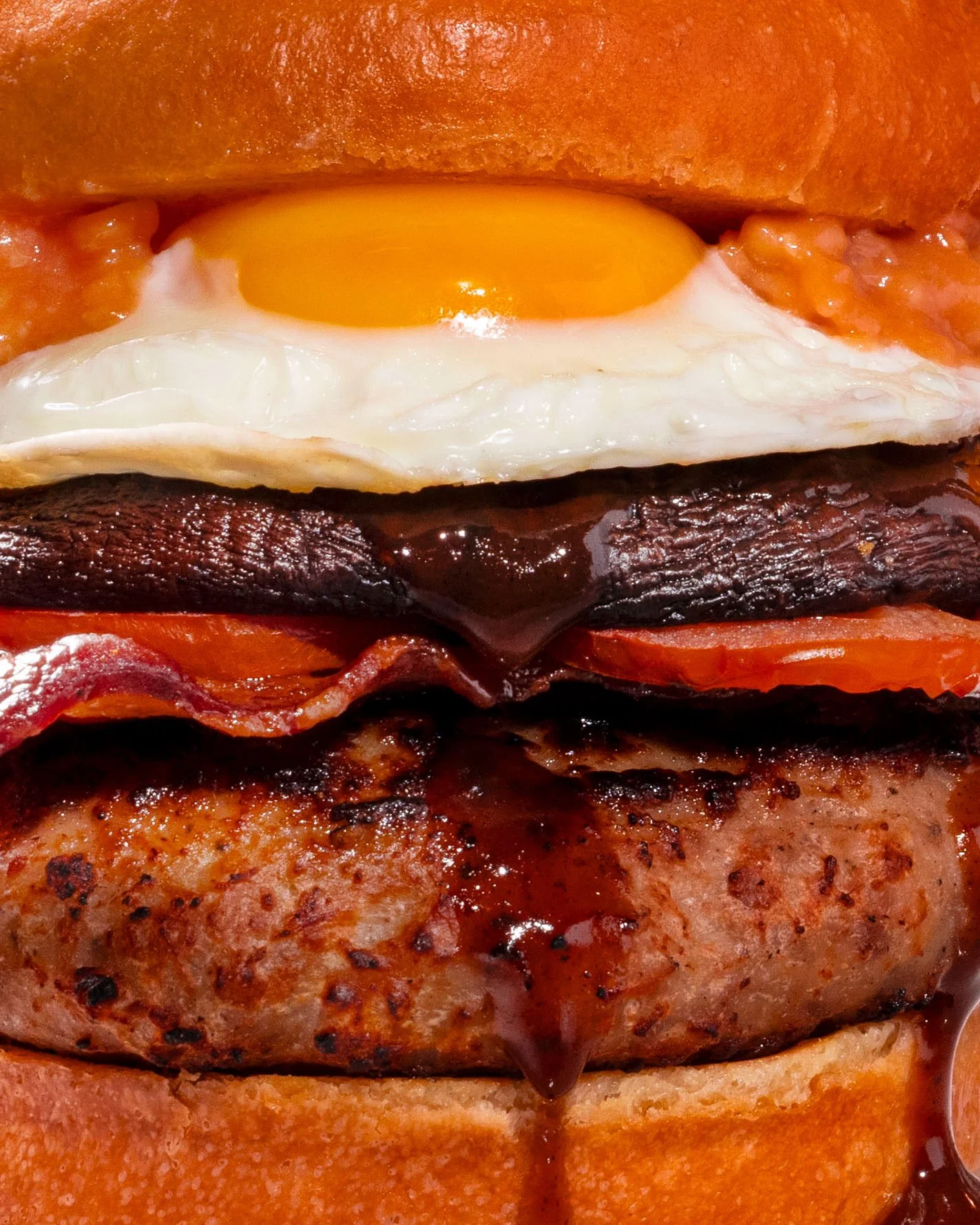 Close-up of the Full English Breakfast Burger with fried egg, bacon, and sausage at Gordon Ramsay Burger, photographed by Michael Rudin