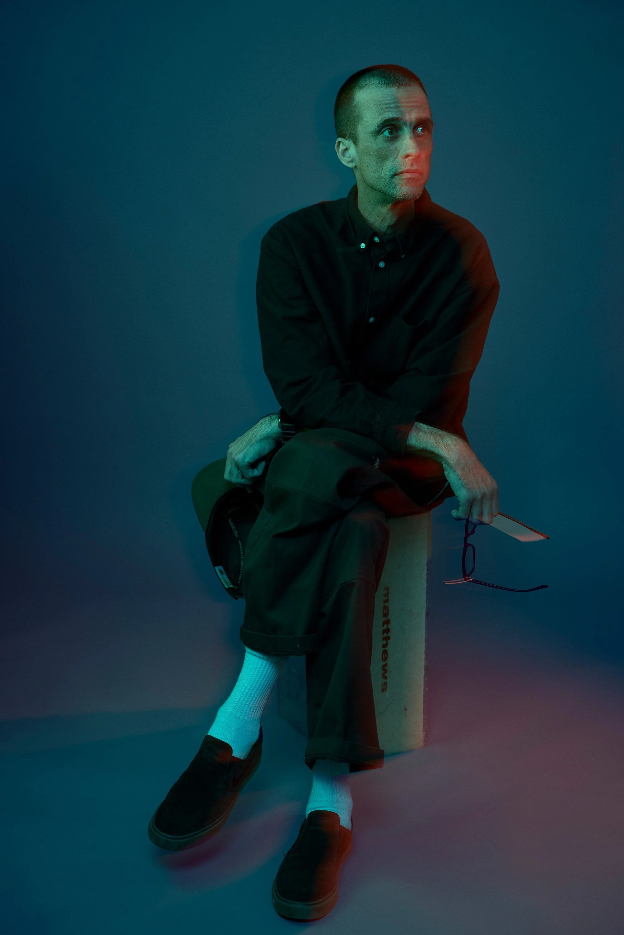 Man seated with a colorful long-exposure light effect, editorial portrait by Michael Rudin