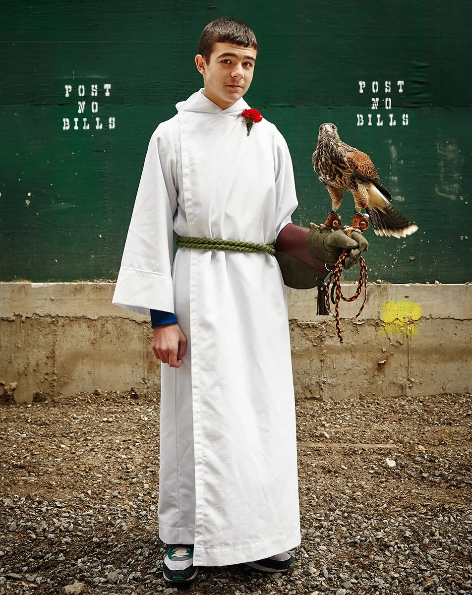 Teenage altar server holding a hawk during the Blessing of the Animals ceremony, editorial portrait by Michael Rudin
