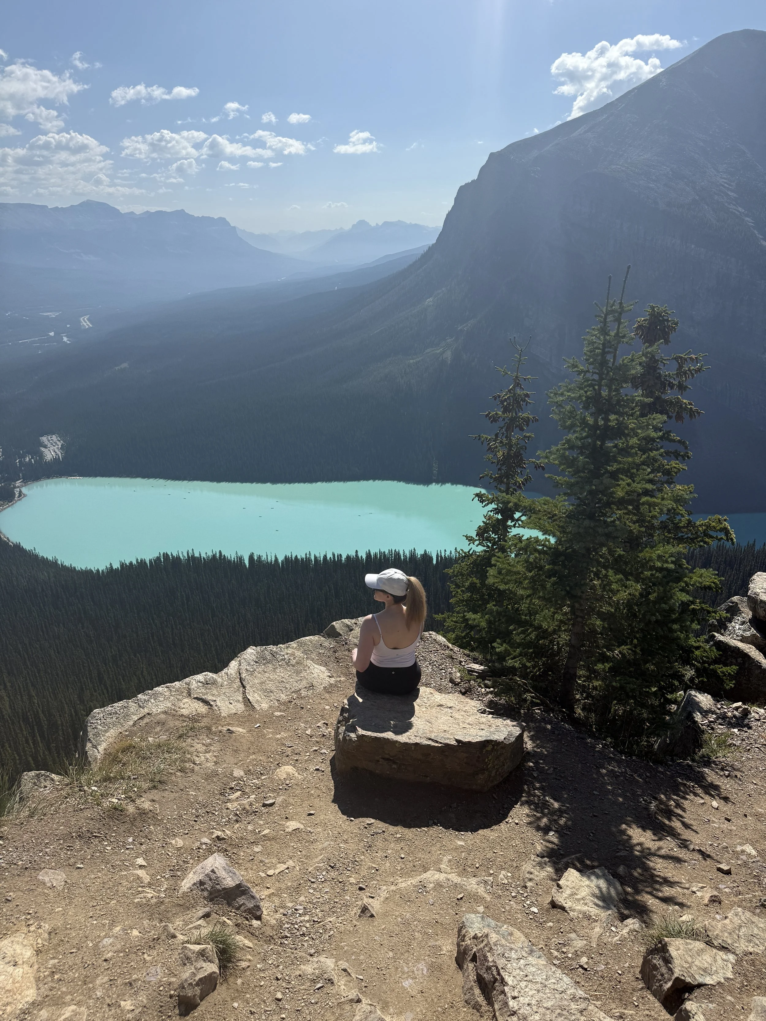 A woman sitting on a rock overlooking Lake Louise