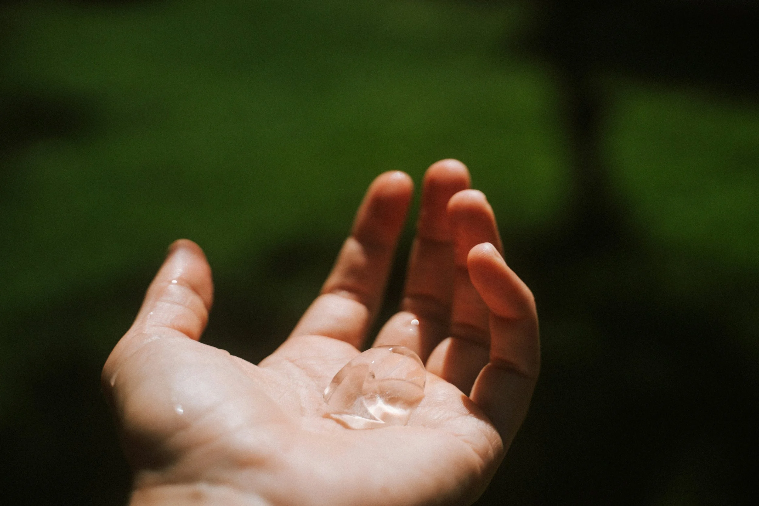 Close-up of a person's hand with multiple small handprints on the palm, held against a blurred green background.