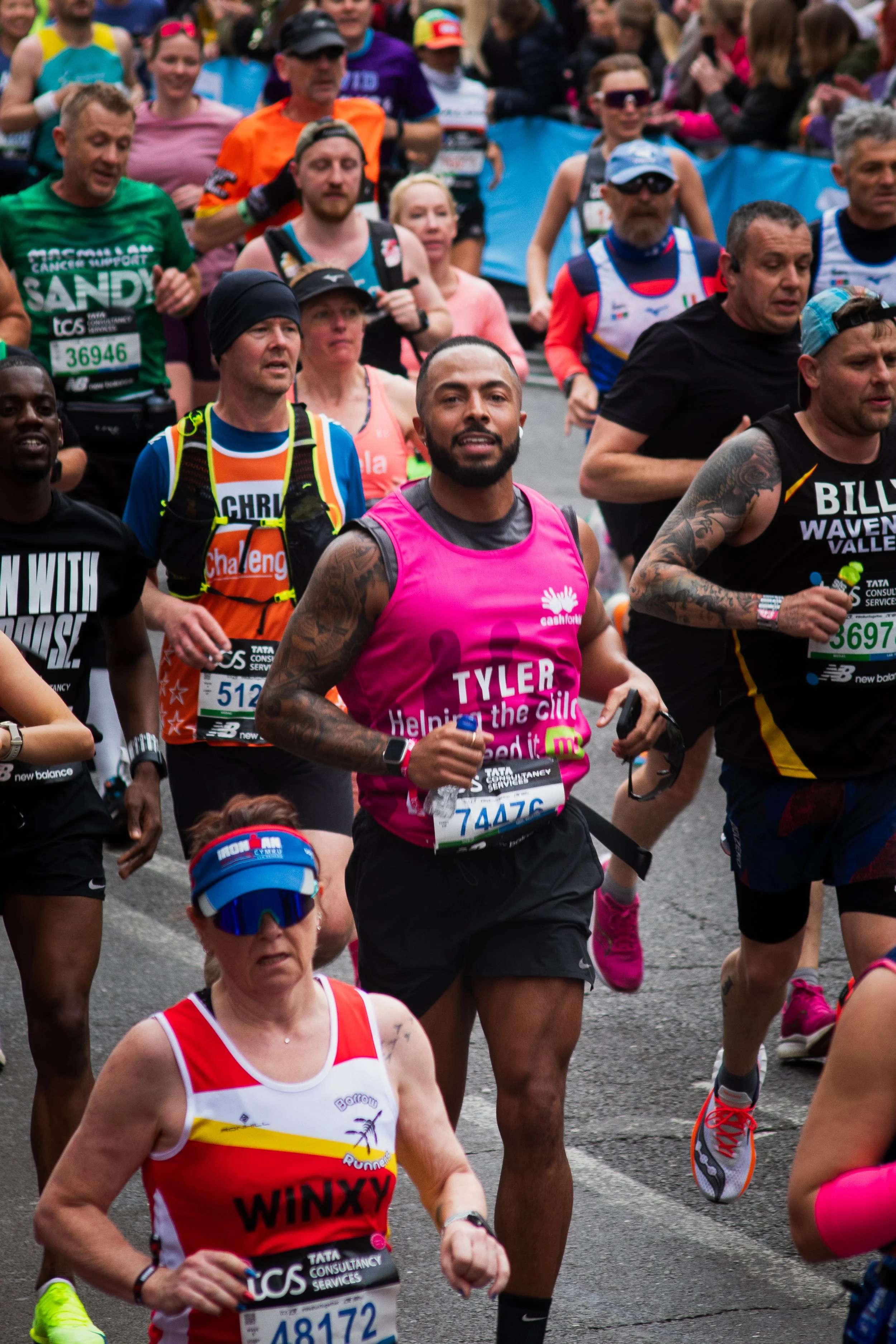 Marathon runners participating in a race, wearing colorful athletic clothing and race bibs, surrounded by spectators.