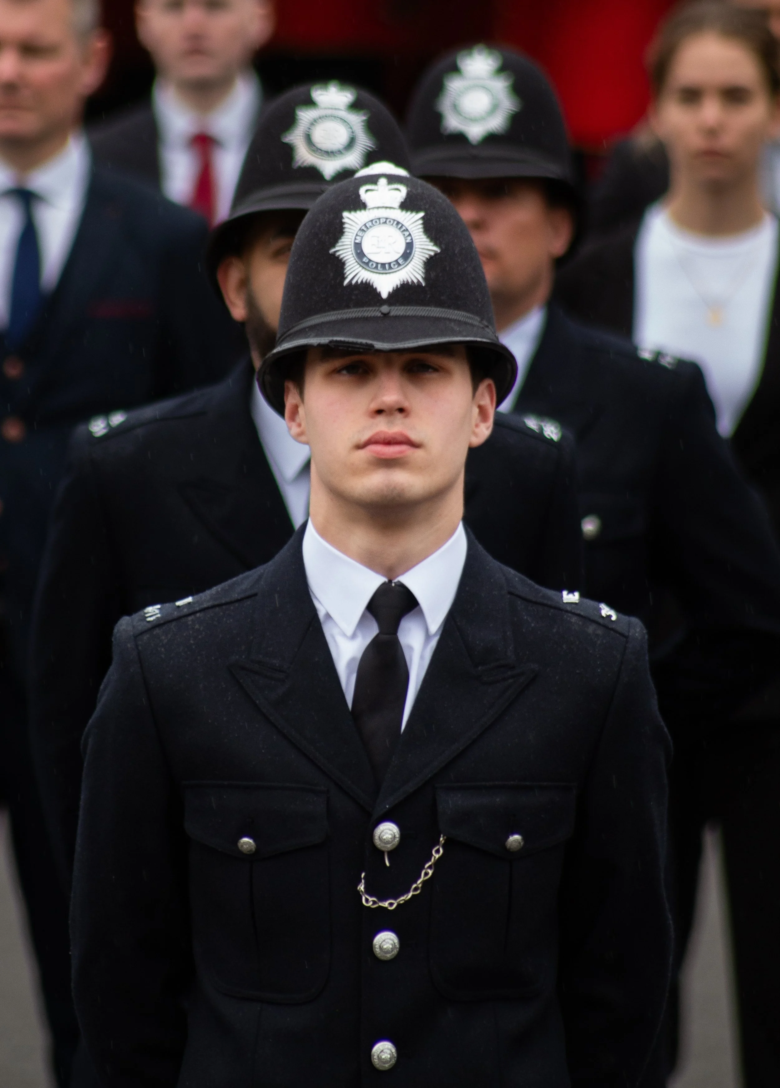 Young police officers in formal black uniform hats with police badges, standing in formation.