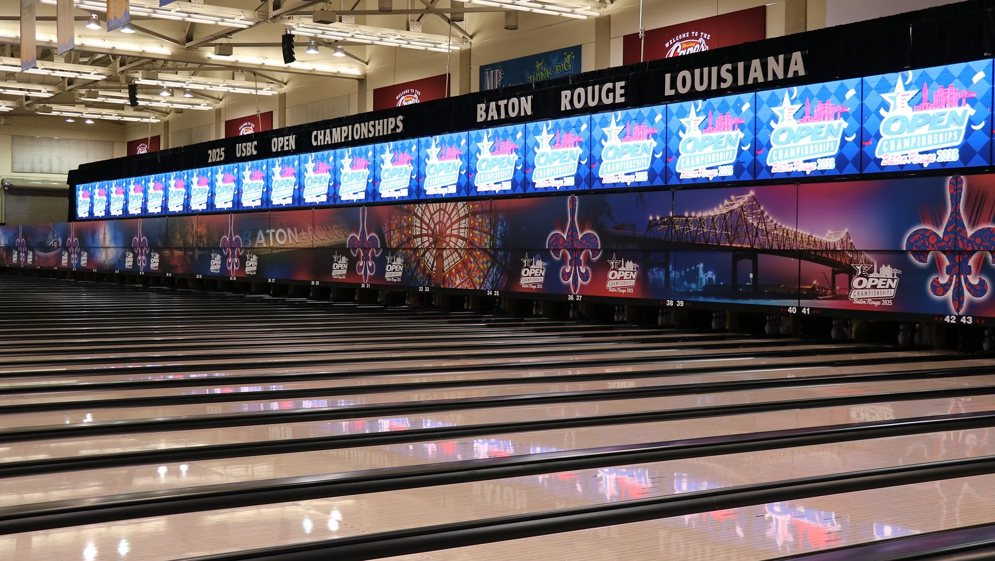 Bowling alley with digital screens displaying banners for the 2025 USBC Open Championships in Baton Rouge, Louisiana. The alley has multiple lanes with pins set at the end.