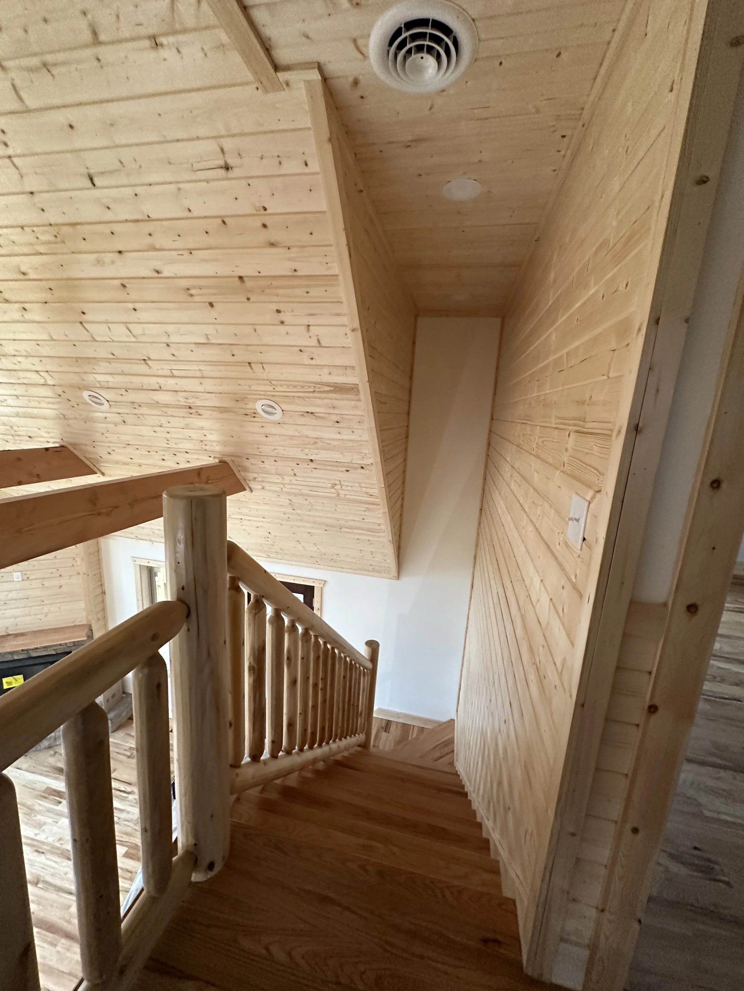 Indoor wooden staircase with wooden paneling on the walls and ceiling, and a wooden railing.