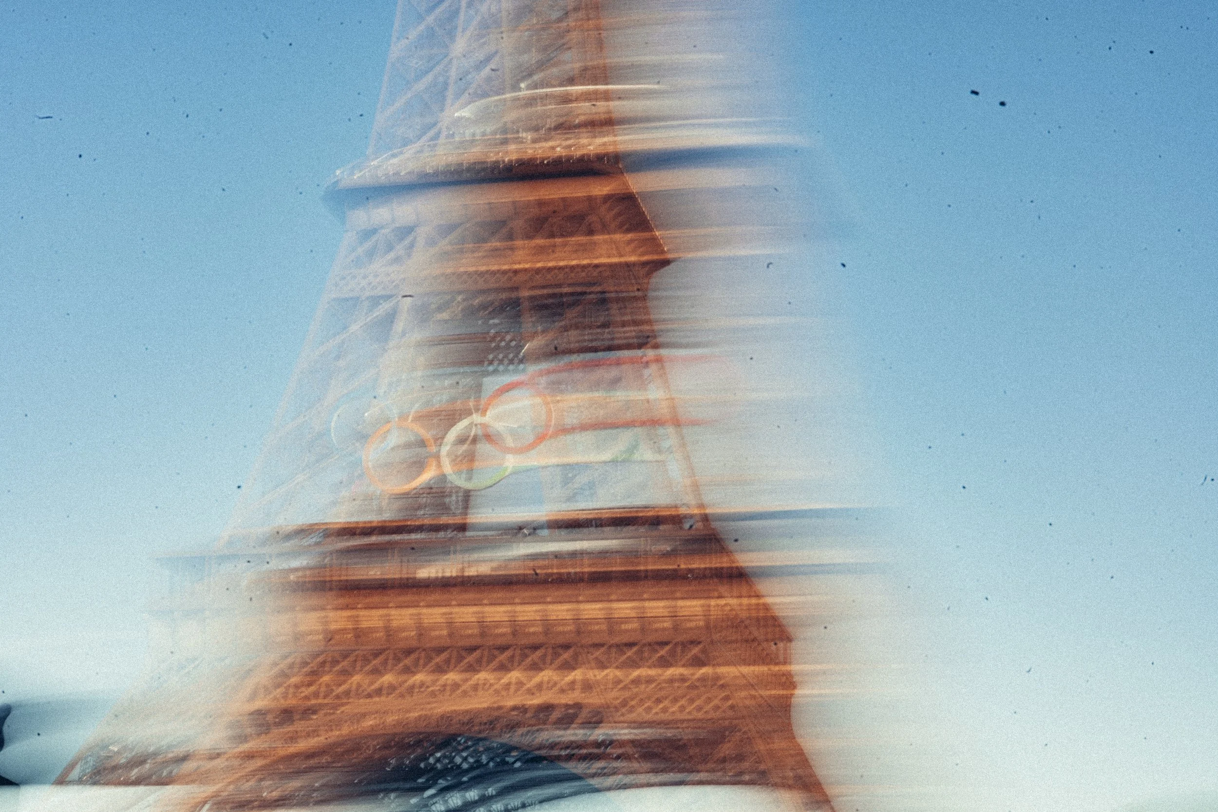 Abstrakte Aufnahme des Eiffel turms mit Bewegungsunschärfe, festgehalten bei Sonnenlicht mit klarem blauen Himmel im Hintergrund.