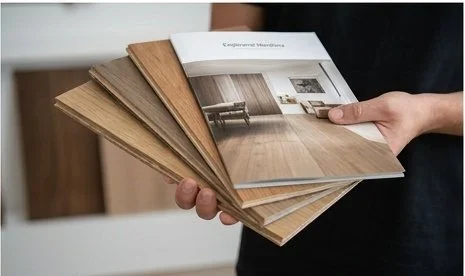 A person holding several sample interior design or furniture catalogs.
