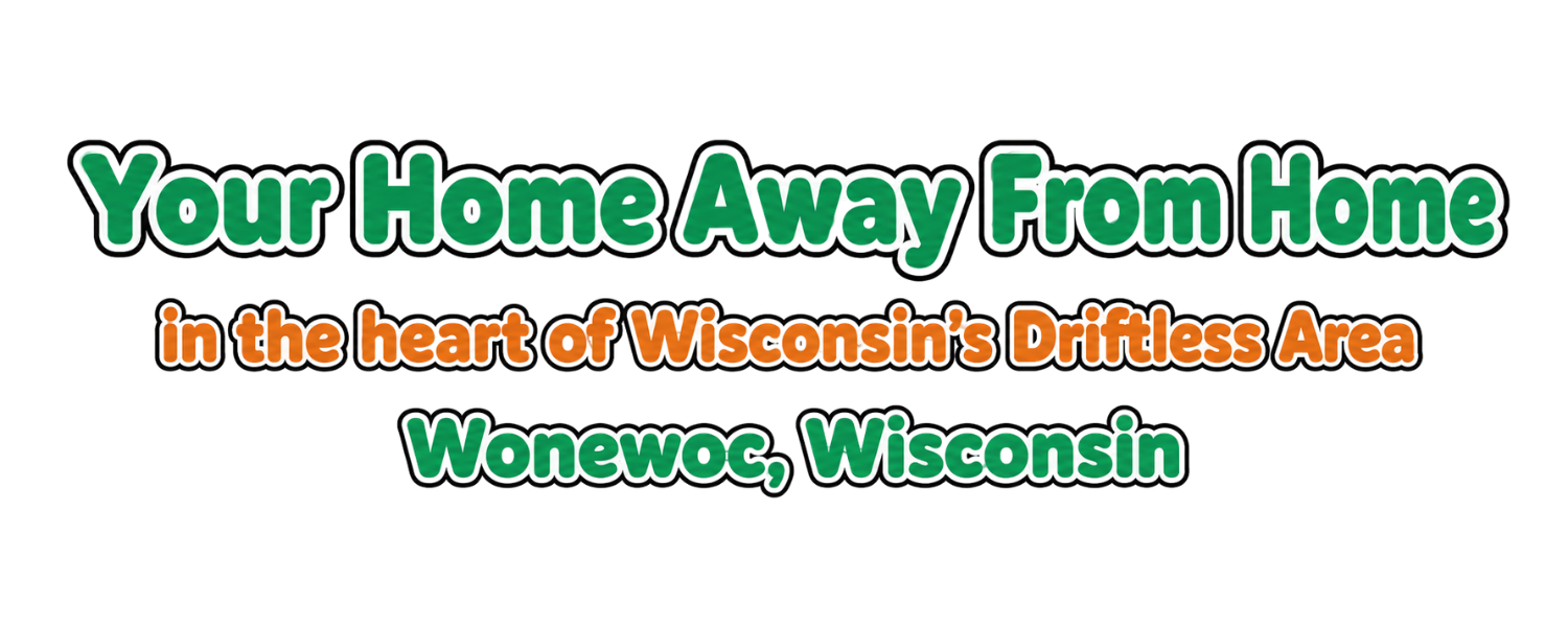 Text graphic promoting a home away from home experience in Wonewoc, Wisconsin, in the heart of Wisconsin's Driftless Area, with colorful text in green, orange, and black.