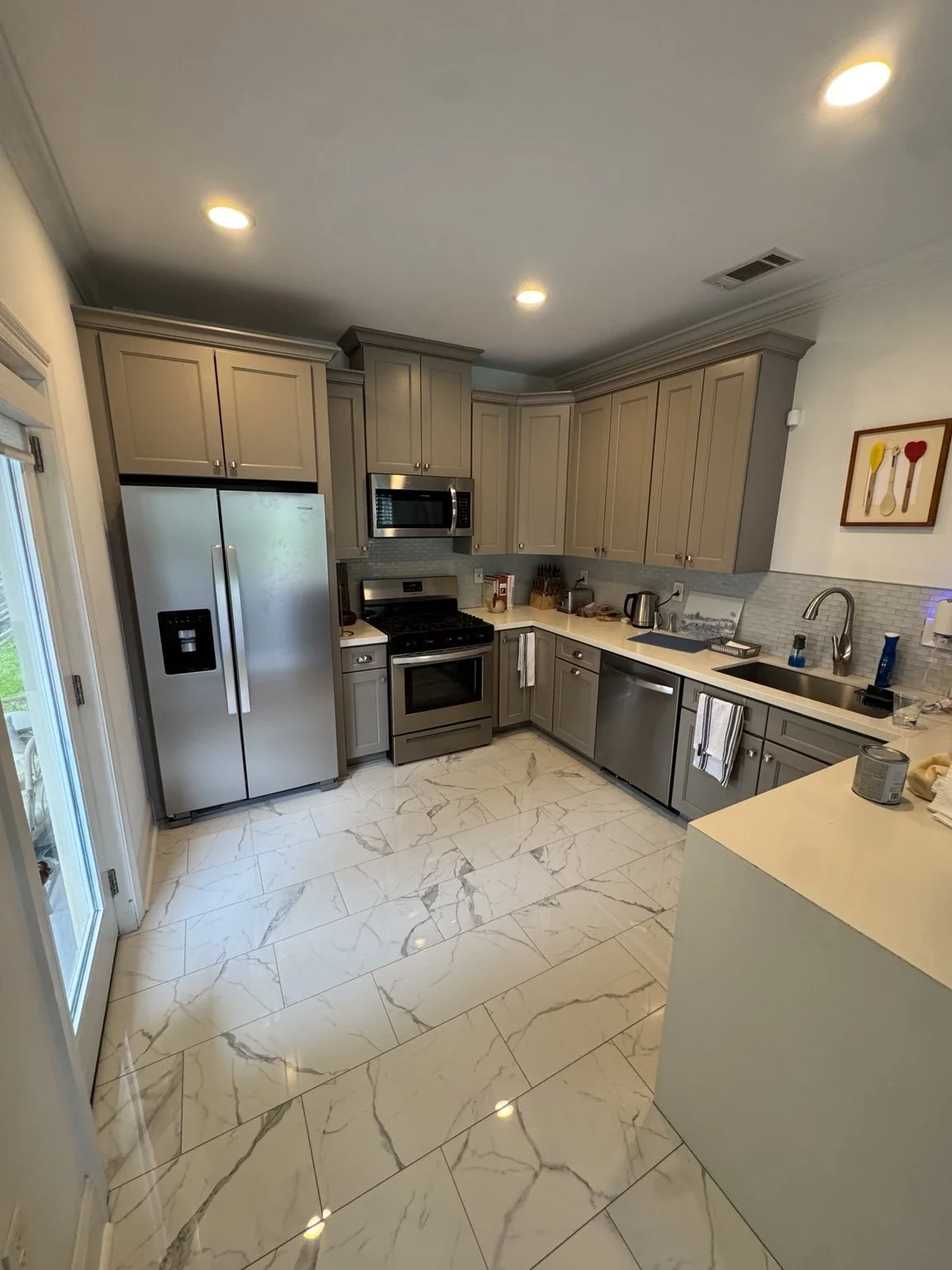 Renovated gray kitchen with marble-look tile flooring and stainless steel appliances.