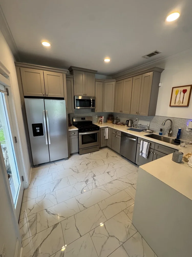 Renovated gray kitchen with marble-look tile flooring and stainless steel appliances.