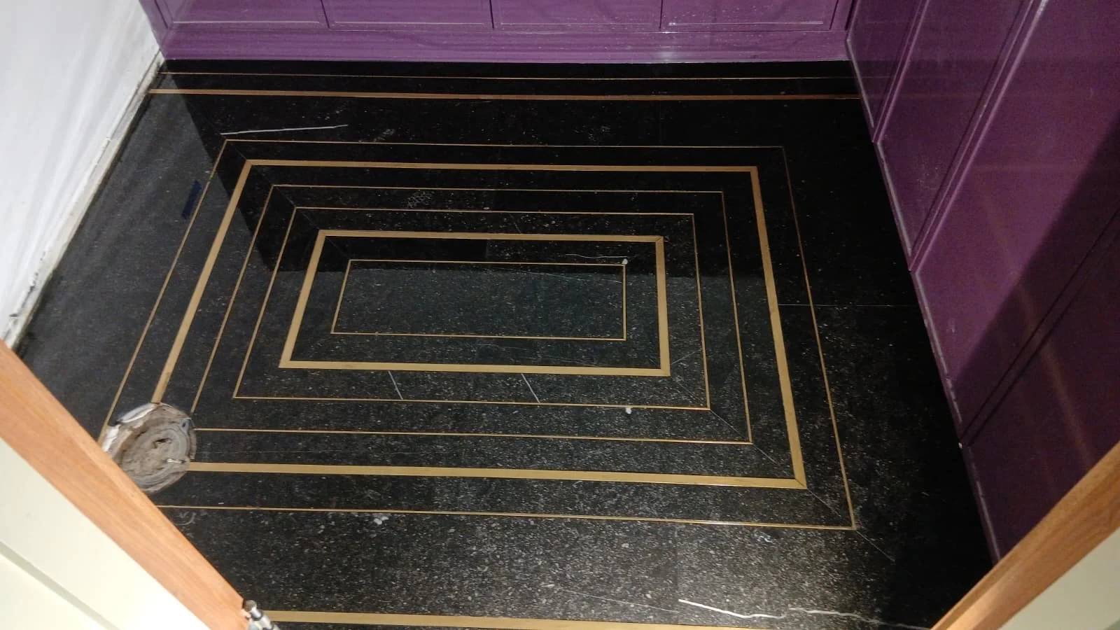 Custom black tile floor with concentric brass inlay lines.
